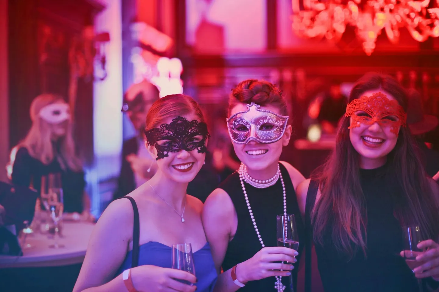 Three women wearing masks and holding glasses